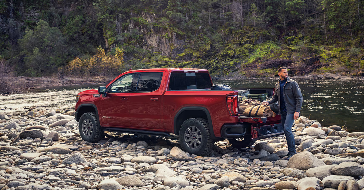 A man loading the bed of a red 2026 GMC Sierra 1500